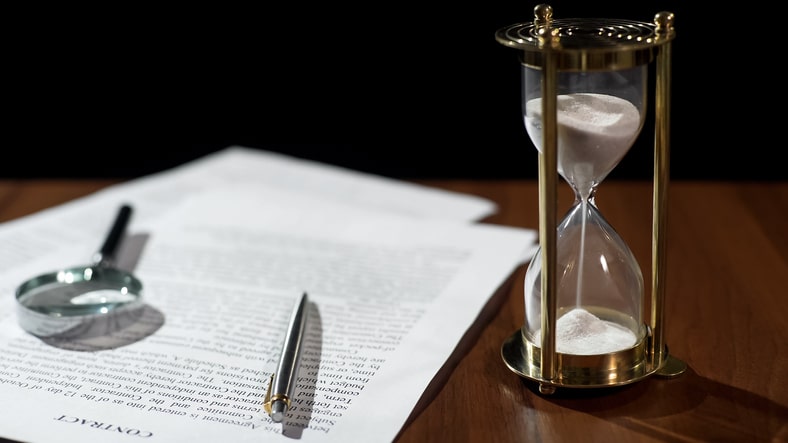 Close-up of legal document and hourglass on table, how long will a lawsuit take