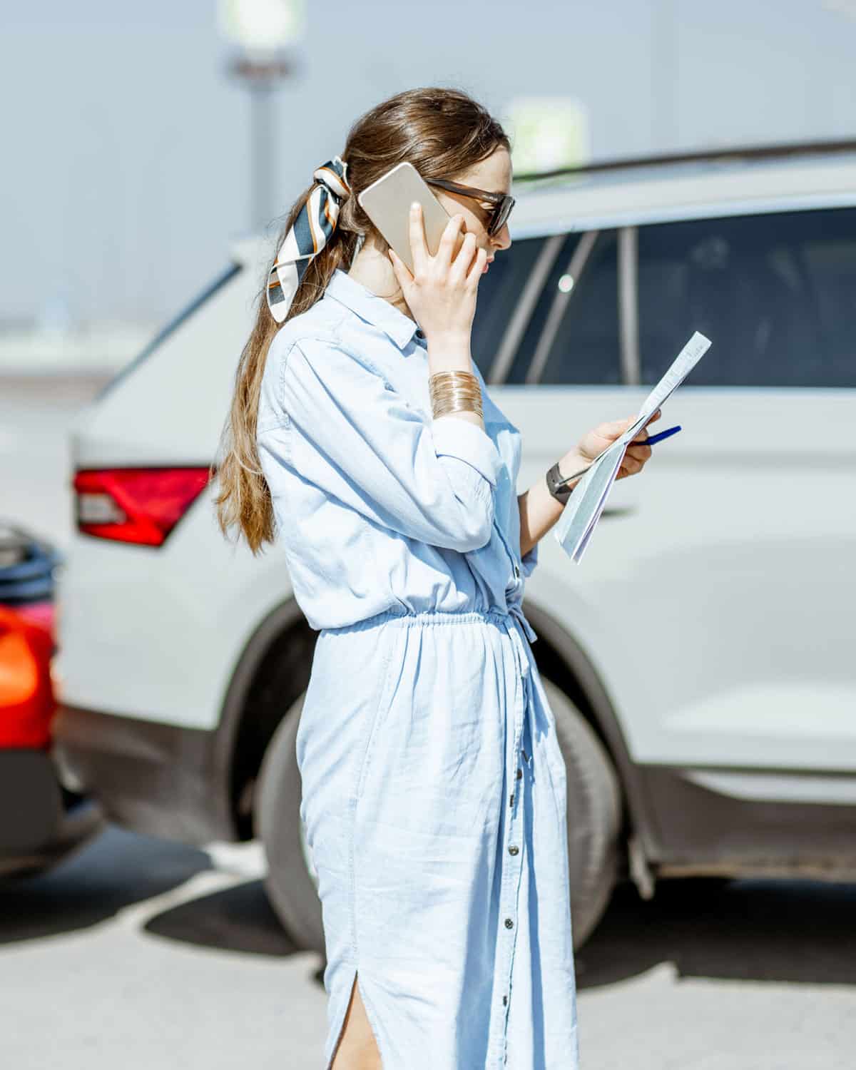 woman in blue dress talks on phone with personal injury attorney in parking lot